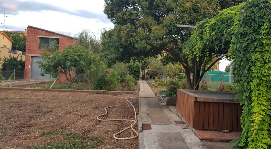 Casa antigua en Navata transformada en proyecto comunitario SOMTRIBU Vista exterior del terreno y la casa adquirida por SOMTRIBU en Navata, rodeada de vegetación y zonas comunes en rehabilitación