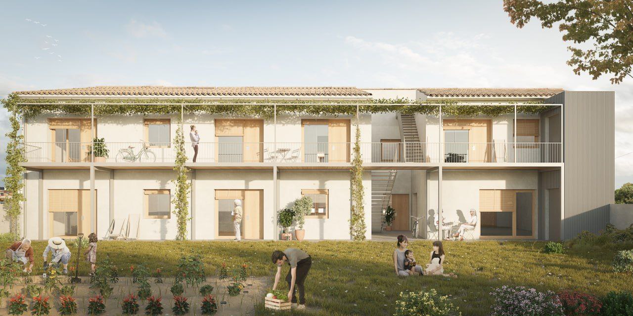 Persones en un espai verd davant d'habitatges cooperatius sostenibles a Navata, projecte comunitari de SOMTRIBU